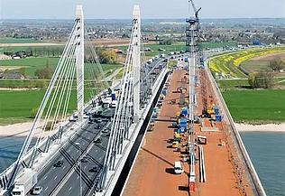 Een foto van de Brug over de Waal/Tacticusbrug, een stalen tuibrug van kokerliggers die de Waal bij Ewijk overspant.