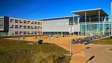 Een foto van de scholengemeenschap met leslokalen over drie verdiepingen, een sportvoorziening en een parkeer- en fietskelder.