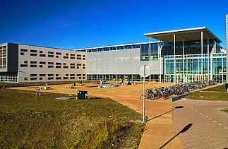 A photograph of the school complex, featuring classrooms spread over three floors, sports facilities and an underground car park and cycle storage area.
