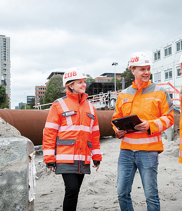 Een foto van ZÜBLIN Nederland medewerkers op een werf die iets aan het bespreken zijn.
