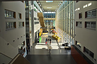 A photograph of the school complex, featuring classrooms spread over three floors, sports facilities and an underground car park and cycle storage area.