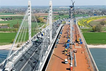 Een foto van de Brug over de Waal/Tacticusbrug, een stalen tuibrug van kokerliggers die de Waal bij Ewijk overspant.