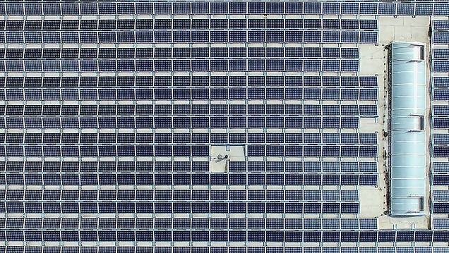 Aerial view of a large number of solar panels on a roof.